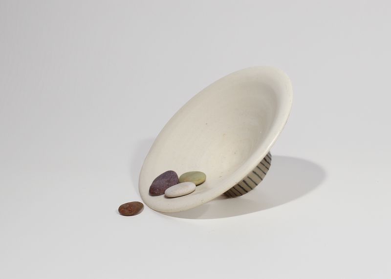 Cream footed bowl tilted, holding pebbles