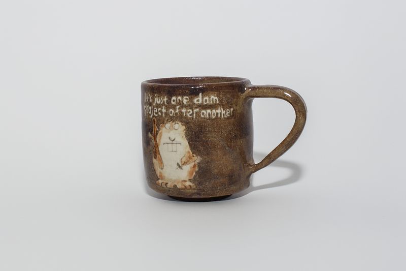 Brown mug with a beaver and "It's just one dam project after another"