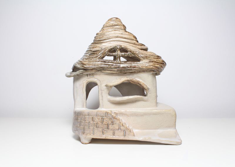 White ceramic house with a coiled thatch roof, front