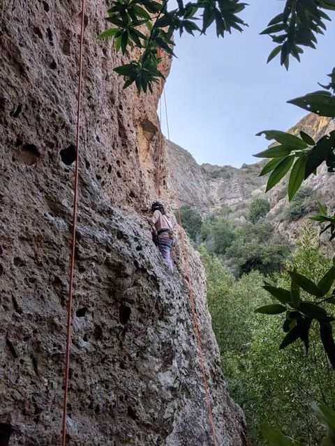 Kay climbing an outdoor rock wall on a top rope