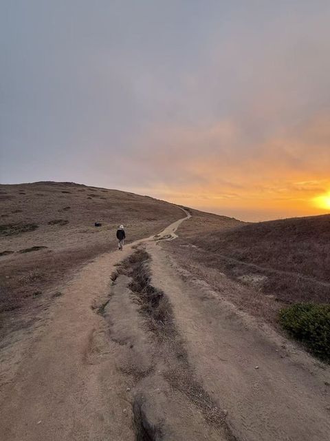 A hiker on a coastal trail at sunset